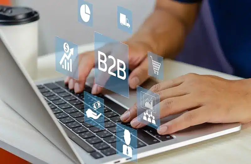 Hands typing on a laptop with B2B digital interface icons, representing API integration and real-time system visibility in fulfillment.