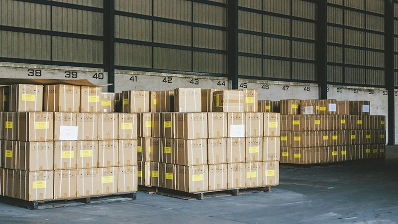 Large stacks of palletized cartons stored in a warehouse, showing common B2B fulfillment challenges such as storage costs and space utilization.