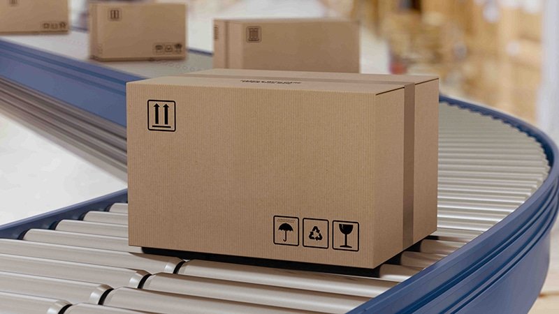 Corrugated shipping box with handling icons moving along a conveyor belt, demonstrating durable and right-sized packaging for B2B logistics.
