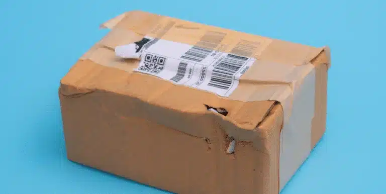 Damaged cardboard box showing incorrect label placement that does not meet Amazon FBA carton labeling standards.
