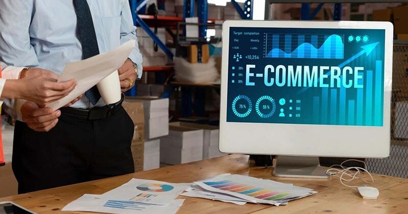 Warehouse team reviewing eCommerce analytics on a computer screen, illustrating data-driven decisions in B2B fulfillment and inventory management.