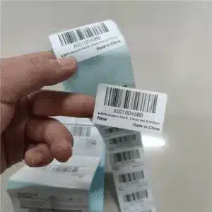 Hand holding FNSKU barcode labels showing improper application on Amazon FBA products.