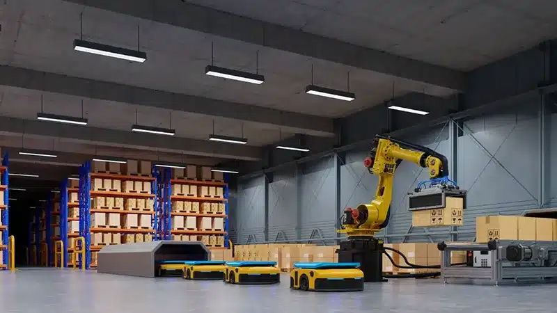 Robotic arm working alongside AGV robots in a modern automated warehouse, showing how robotics improve accuracy and speed in B2B fulfillment.