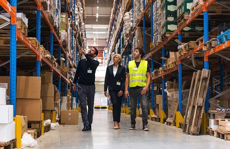 A warehouse manager guiding team members through inventory shelves, showing how B2B fulfillment optimizes storage, stock control, and operational efficiency.