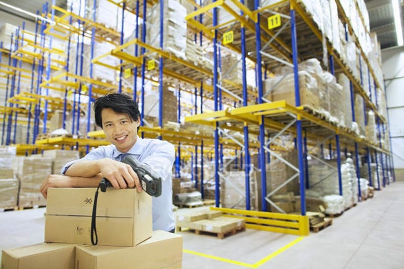 Smiling warehouse staff leaning on parcels, highlighting efficient handling and packing in B2B fulfillment services.