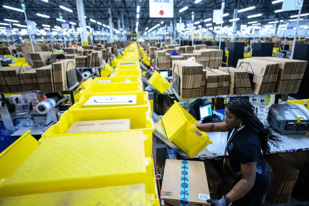 Amazon FBA worker inspecting bins and cartons during fulfillment preparation.