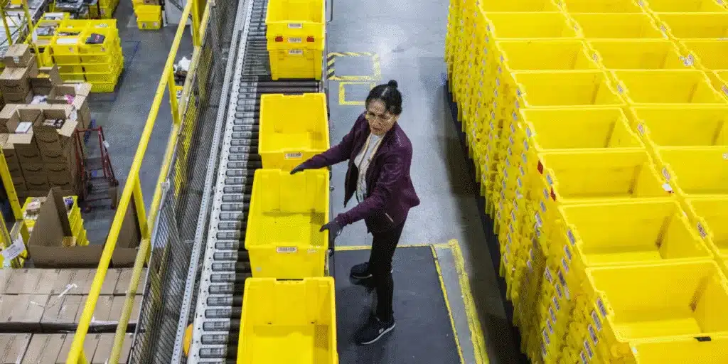 Amazon worker inspecting yellow tote bins during the fulfillment process.