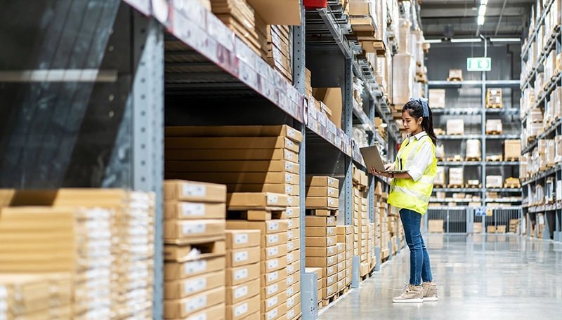 Worker checking SKU-level apparel inventory in a warehouse for accurate fulfillment operations