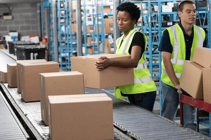 Warehouse workers performing B2B pick and pack operations on a conveyor line inside a China fulfillment center