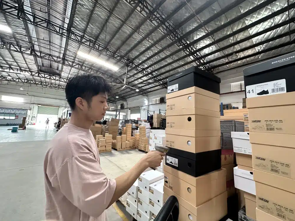 Warehouse employee scanning a shoebox barcode to verify inventory during ecommerce fulfillment