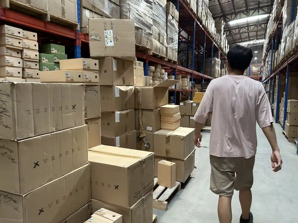 Warehouse worker walking between racks and palletized cartons in a China 3PL inventory storage area