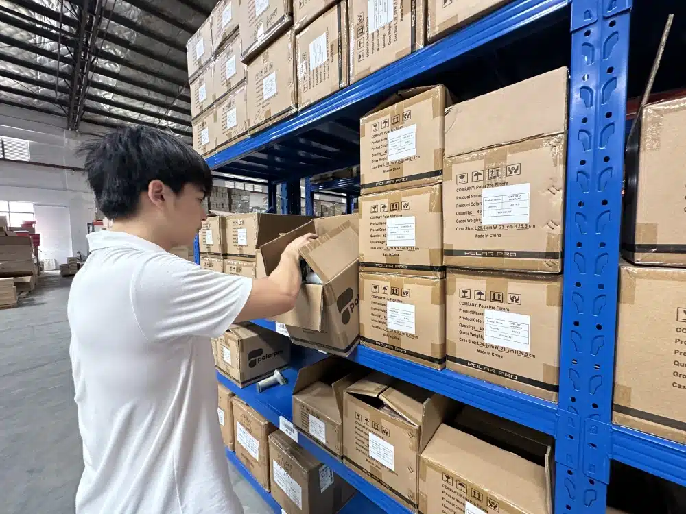 Warehouse employee selecting an item from a labeled carton in a China 3PL order-picking area