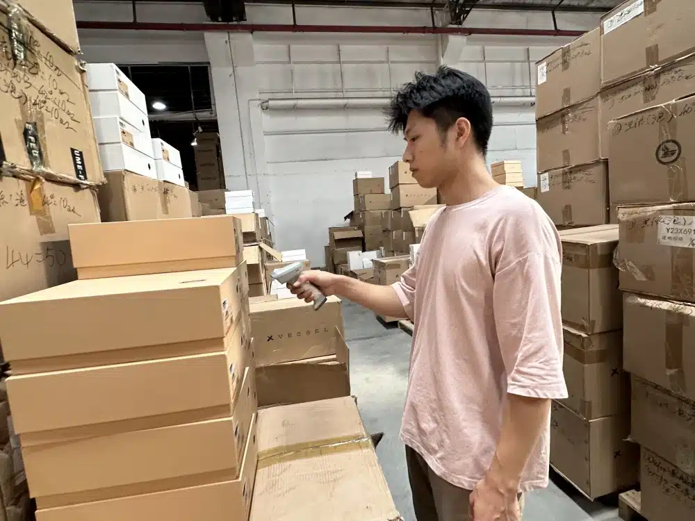Warehouse employee scanning shoebox labels during inventory checks for Black Friday fulfillment preparation