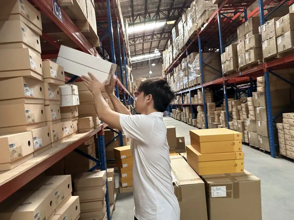 Warehouse worker retrieving shoeboxes from storage racks during China 3PL order picking