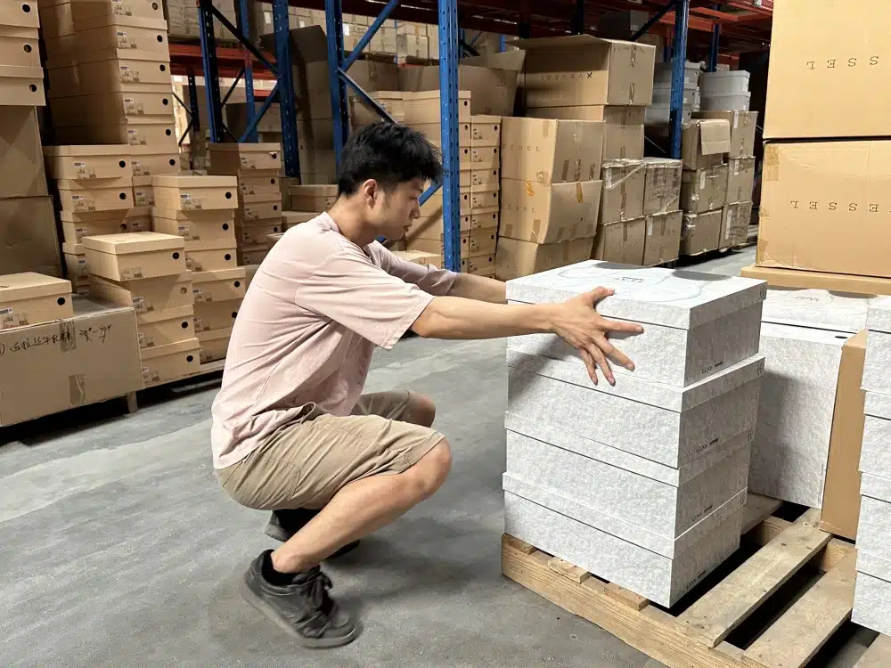 Warehouse worker arranging boxed products on a wooden pallet in a China 3PL storage area