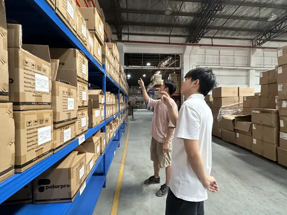 Two warehouse employees reviewing labeled cartons on storage racks during an inventory assessment