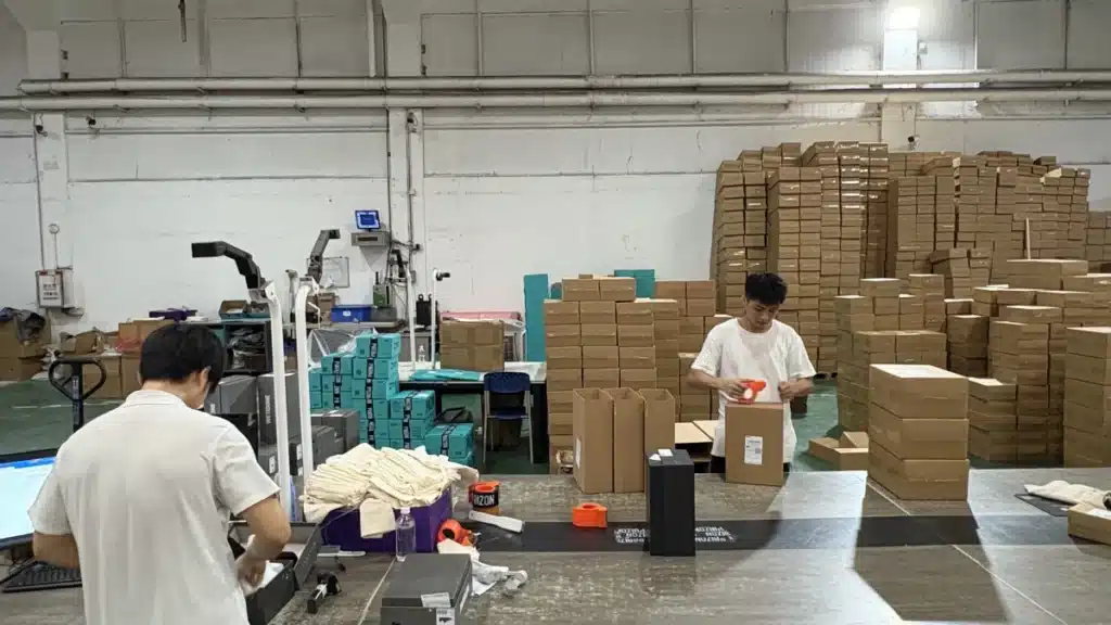 Warehouse fulfillment team packing ecommerce orders at packing stations, showing picking, packing, packaging materials, and labor costs per order.