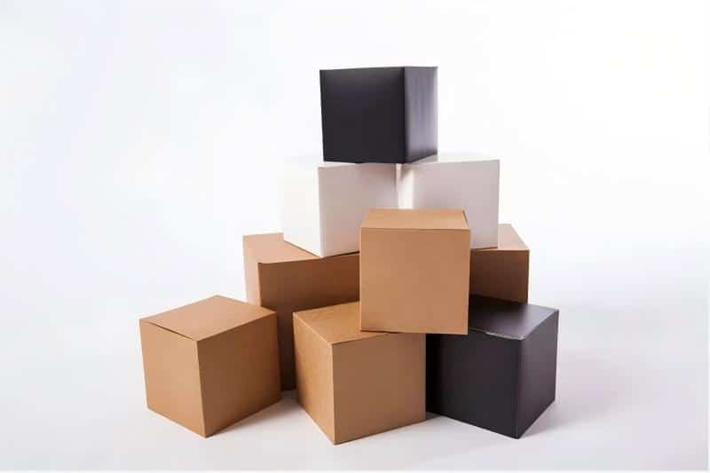 Stack of various cardboard boxes in different colors and sizes, representing kitting and packaging solutions for board game crowdfunding campaigns