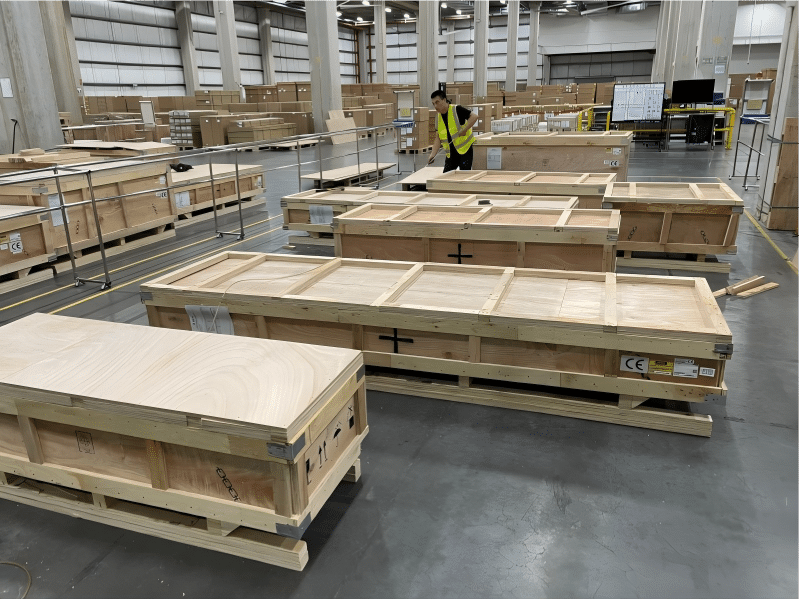 Large wooden shipping crates in a warehouse, labeled with CE certification and prepared for international shipment of tech products