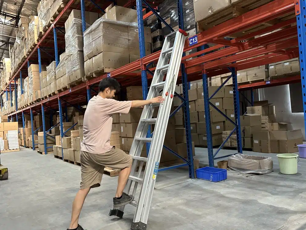 Warehouse worker climbing a ladder beside stocked racks, illustrating access planning for Q4 fulfillment