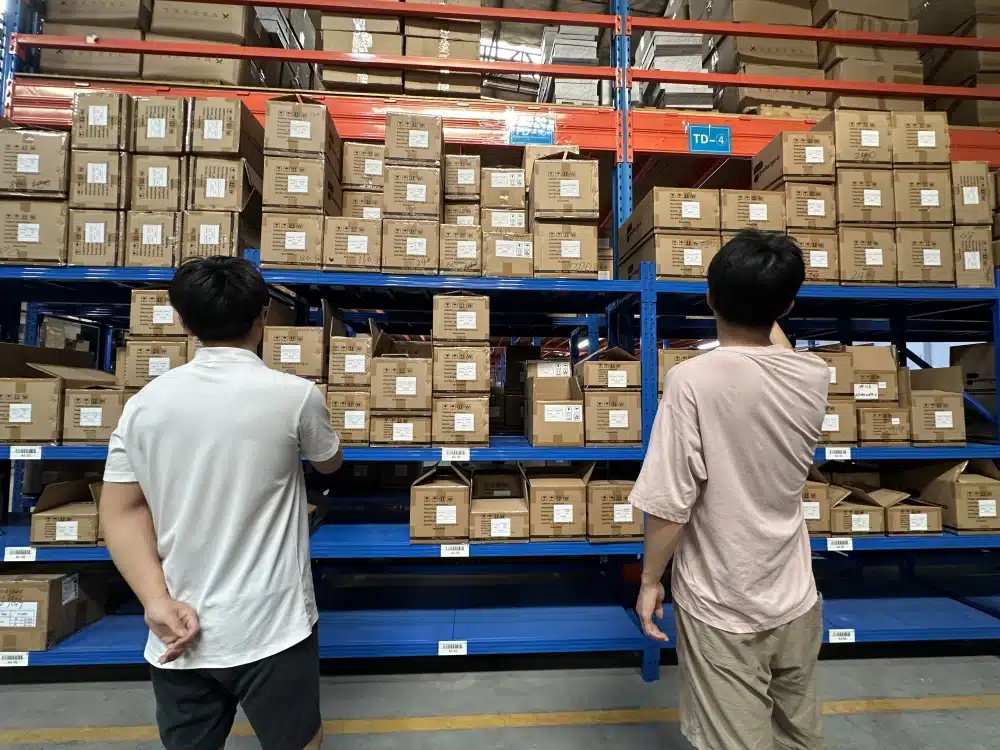 Two warehouse employees reviewing labeled inventory on storage racks in a China fulfillment center