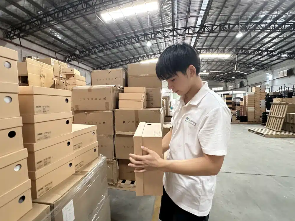 Warehouse employee inspecting blue and black shoes at a packing station for ecommerce order fulfillment