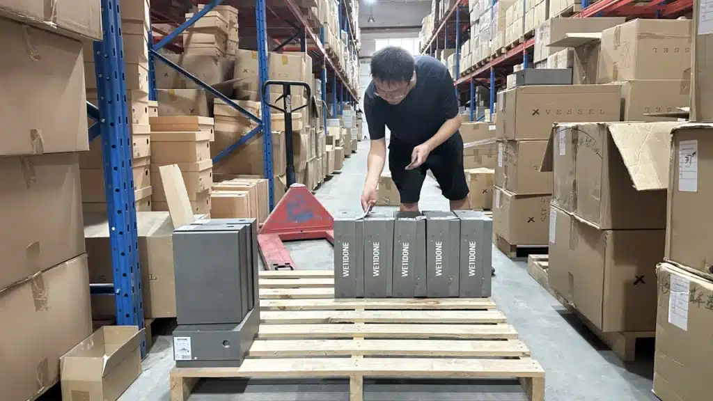 Warehouse worker organizing bulk product inventory on pallets for 3PL fulfillment after transitioning from a print-on-demand business model.