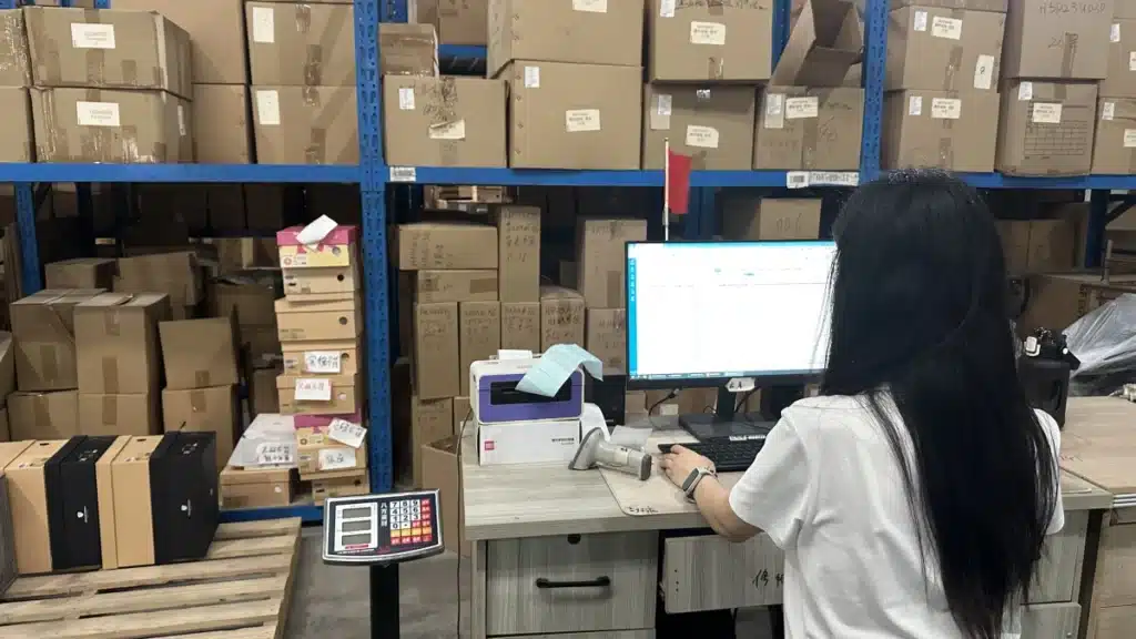 Warehouse employee reviewing WMS inventory data at a fulfillment station, demonstrating real-time inventory control and 3PL performance monitoring.