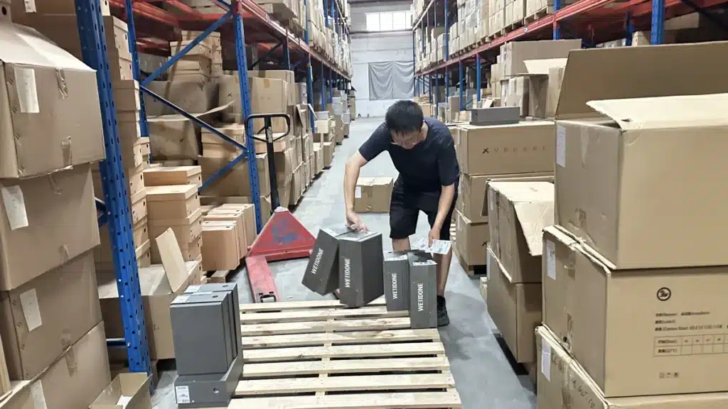 Warehouse worker organizing ecommerce inventory on pallets, representing inventory retrieval, stock reconciliation, and transfer planning when switching 3PL providers.