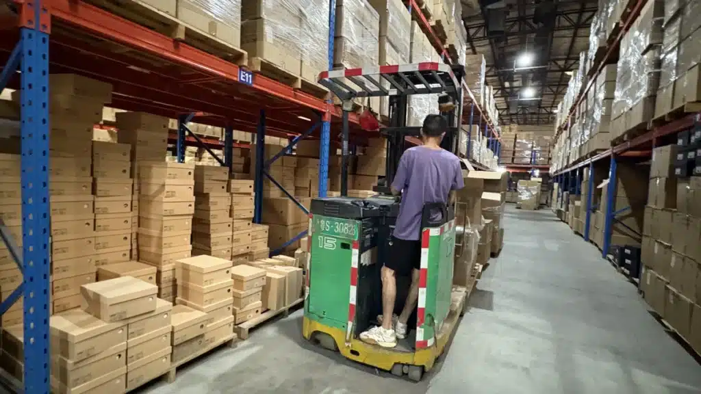 Warehouse worker operating material handling equipment between stocked racks, illustrating 3PL inventory management, warehouse operations, and fulfillment continuity planning.