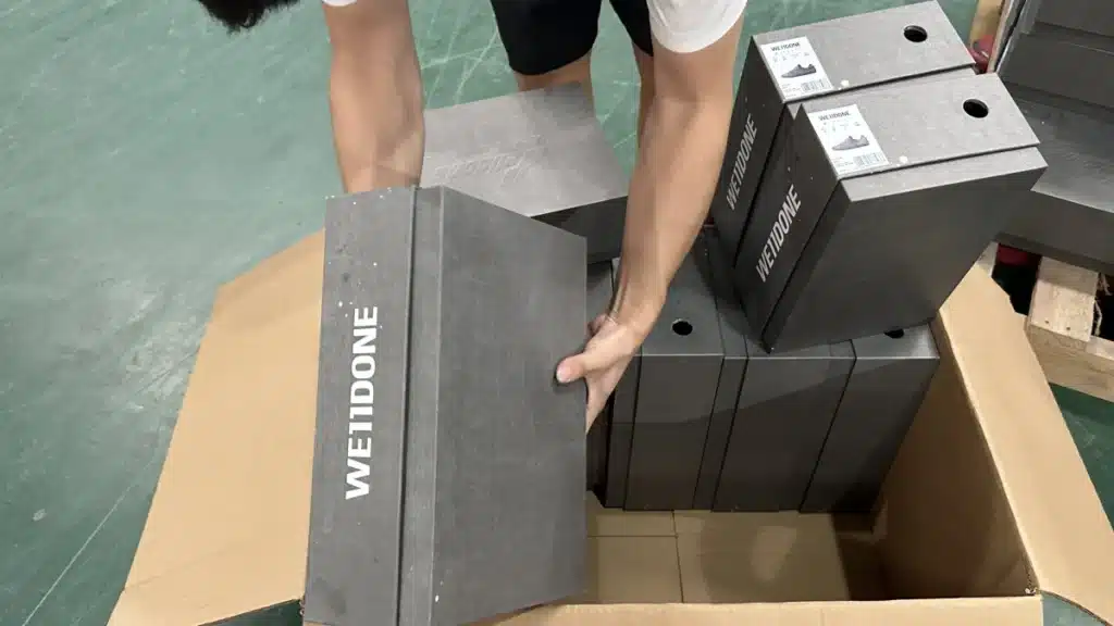 Warehouse worker carefully packing the correct shoe products into a shipping carton to improve order accuracy rate and prevent fulfillment errors.
