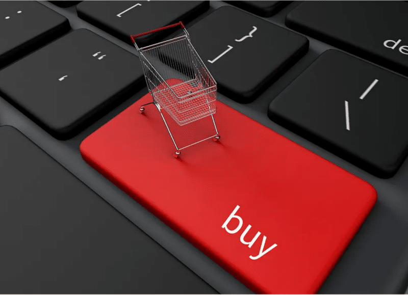 Miniature shopping cart placed on a red ‘buy’ key of a laptop keyboard, symbolizing online pre-order purchases and digital conversion optimization for new product launches.