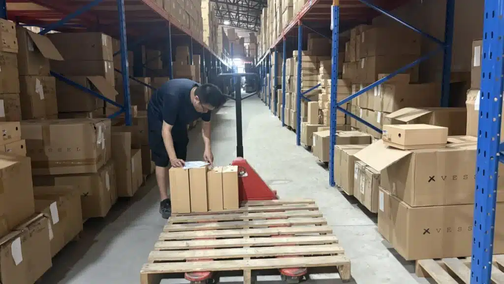 Warehouse worker picking ecommerce products from organized inventory as part of a fast 3PL fulfillment process designed to reduce order processing time.