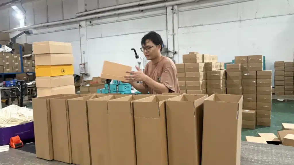 Warehouse worker sorting ecommerce products into cartons, illustrating inventory allocation, SKU distribution, and order fulfillment across a diversified warehouse network.