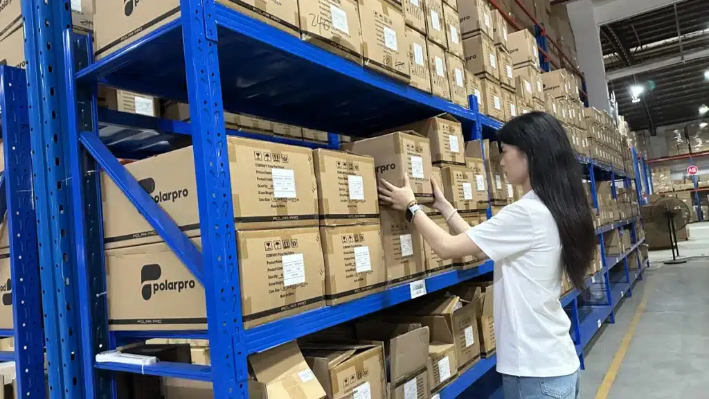 Warehouse worker picking labeled ecommerce inventory from storage racks as part of a data-driven fulfillment process for choosing the best shipping method for each order.
