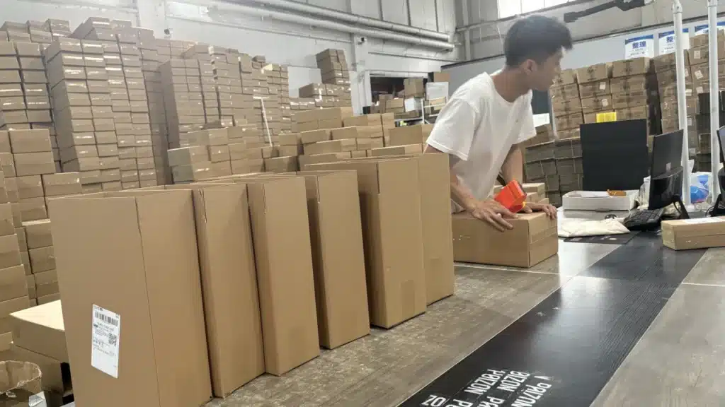 Warehouse worker preparing packaged orders at a fulfillment station, showing professional pick and pack fulfillment for small eCommerce businesses.