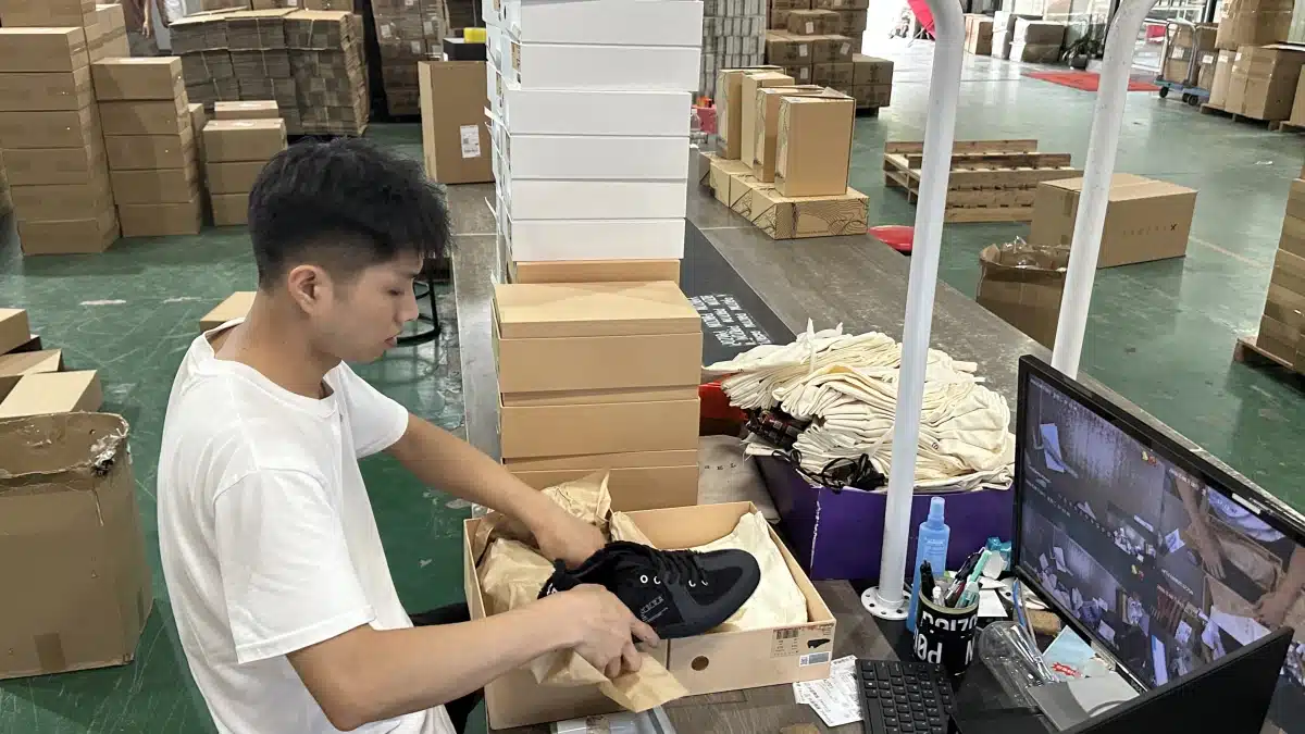 Fulfillment worker packing customer orders in a warehouse as part of an eCommerce shipping strategy focused on cost control and checkout conversion.
