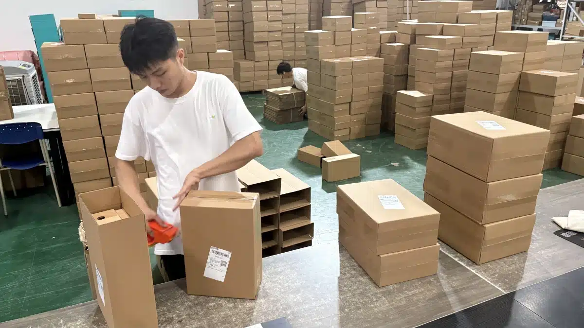 Warehouse worker packing customer orders during the pick and pack process for eCommerce order fulfillment and shipment preparation.