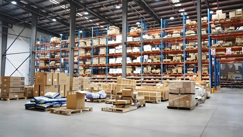 Stacks of cardboard boxes and pallets ready for shipment in a fulfillment center, representing the packing labor and materials involved in calculating pick and pack costs.