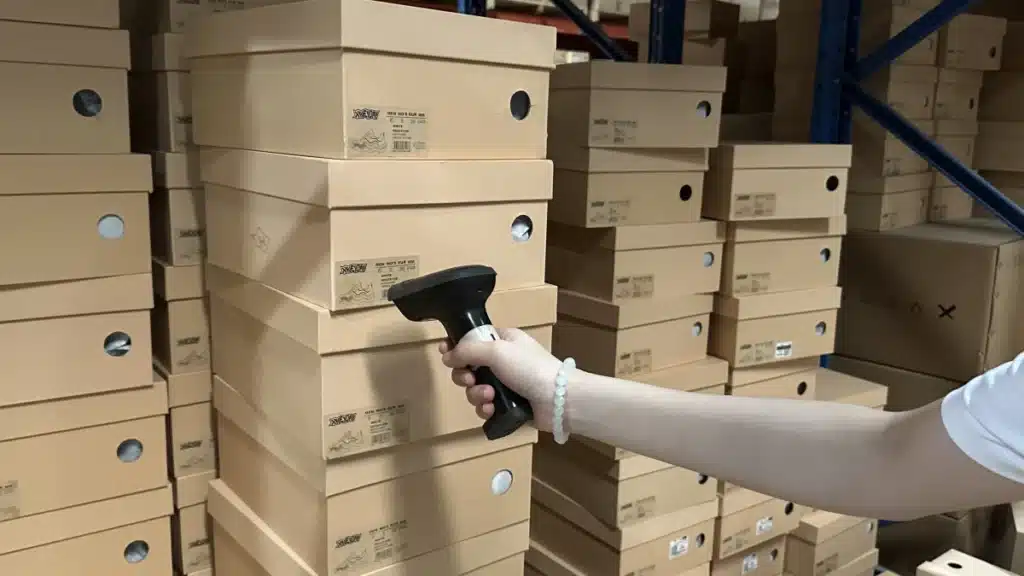 Warehouse worker scanning product barcodes during the picking stage of pick and pack fulfillment to verify SKUs and improve order accuracy.
