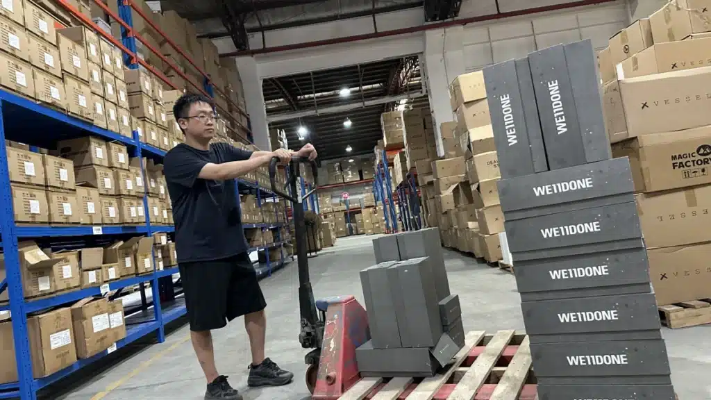 Warehouse worker moving products with a pallet jack during eCommerce order fulfillment, demonstrating efficient inventory handling and warehouse operations.