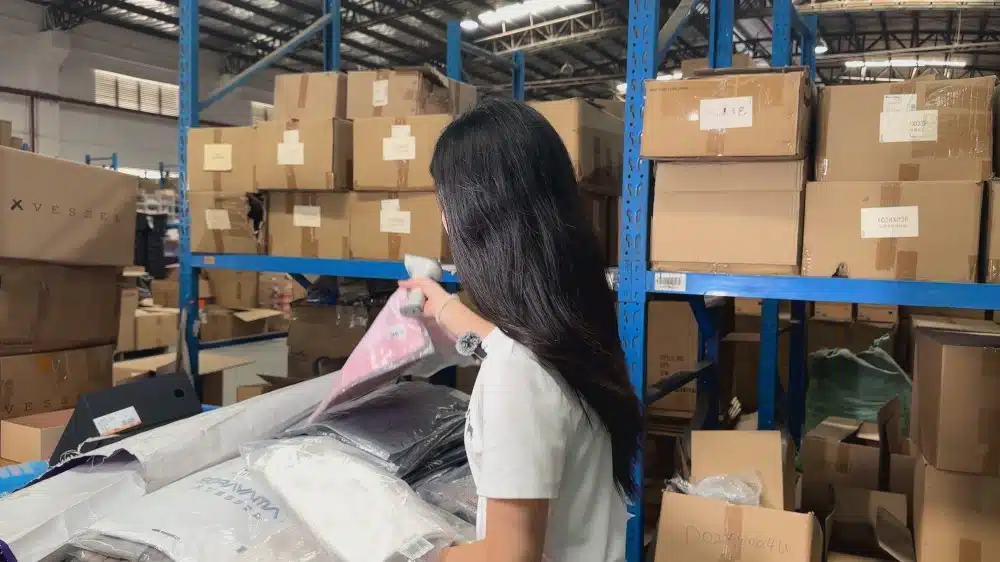 Warehouse employee organizing products on shelves for dropshipping inventory control and ecommerce order processing