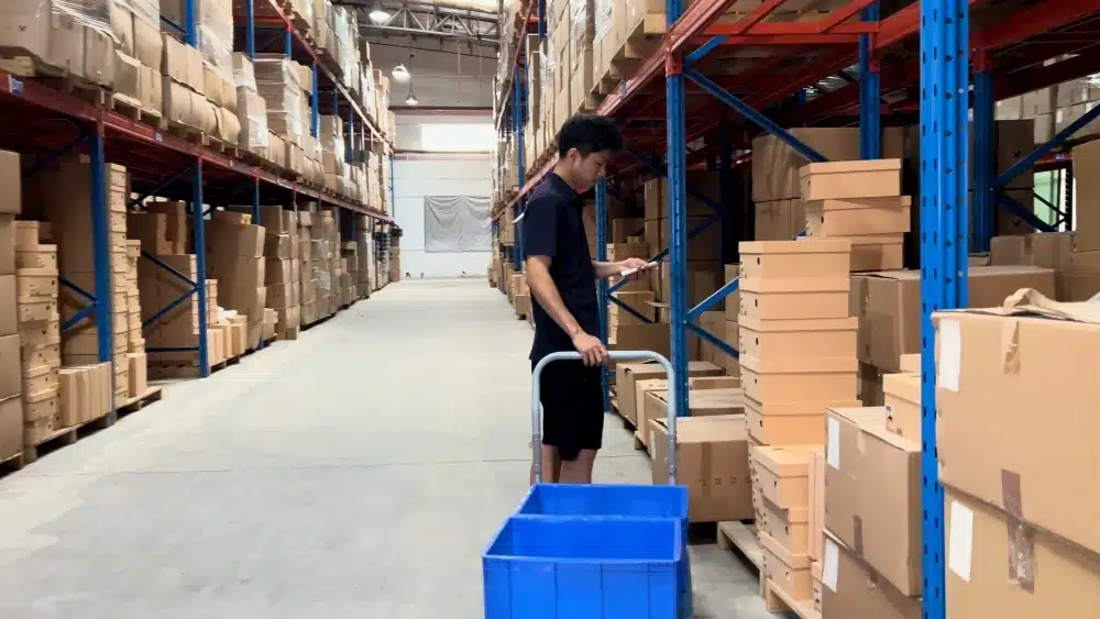 Warehouse worker picking inventory from storage racks in a China 3PL center for Shopify order fulfillment and global shipping