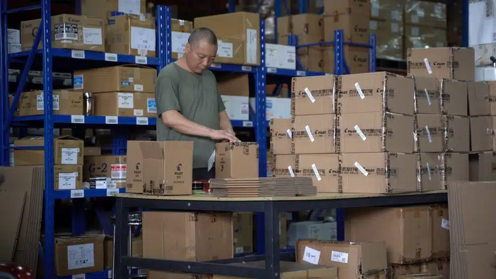 Worker preparing ecommerce packages in a warehouse supporting reusable packaging, reverse logistics, and circular supply chain management