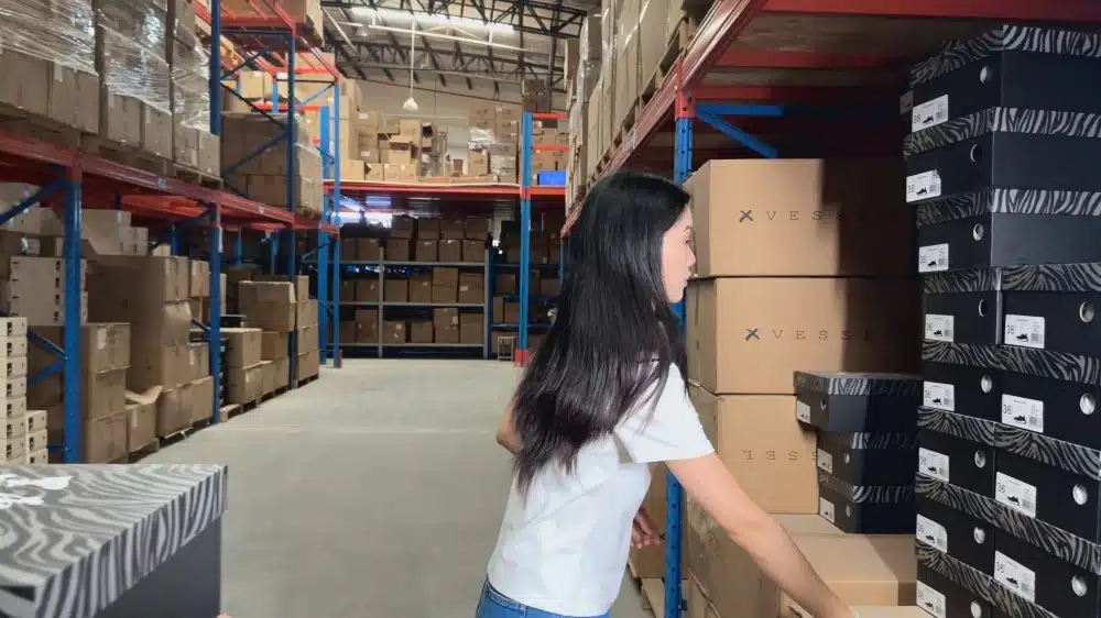 Warehouse employee organizing products on storage shelves with digital inventory management and warehouse workflow systems